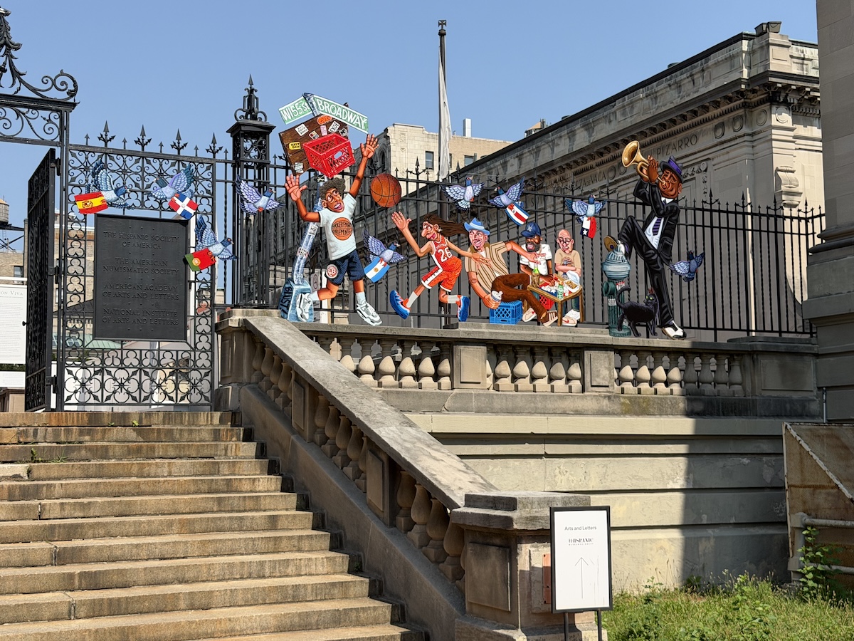 An ornate iron gate with painted cutouts of scenes related to West Harlem and Washington Heights